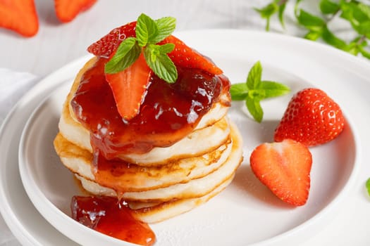 Mini pancakes with strawberry jam and strawberries.