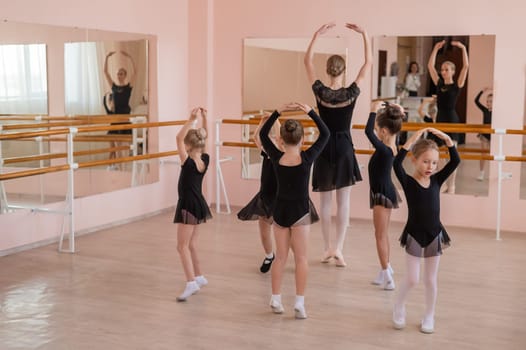 Children's ballet school. Caucasian woman teaching ballet to little girls