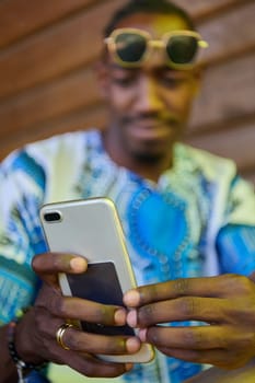 African American teenager adorned in traditional Sudanese clothing, seamlessly navigating the digital world with a smartphone in hand.
