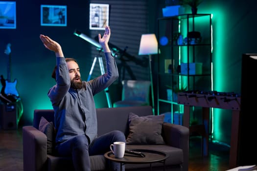 Jolly man clapping hands after favorite team wins while watching live sports event broadcasted on TV. Happy supporter applauding own club, enjoying football competition victory