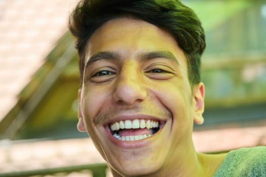 A closeup of a Middle Eastern man with a broad smile and beautiful white teeth, radiating warmth and joy.