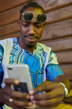 African American teenager adorned in traditional Sudanese clothing, seamlessly navigating the digital world with a smartphone in hand.