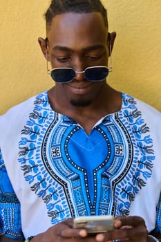 African American teenager adorned in traditional Sudanese clothing, seamlessly navigating the digital world with a smartphone in hand.