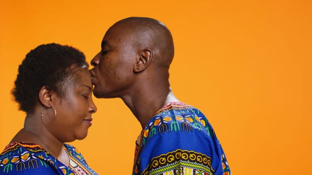 Caring man giving a kiss on his girlfriend forehead, presenting his love and affection for her. Romantic boyfriend kissing his partner, showing sincere deep feelings on camera. Close up.