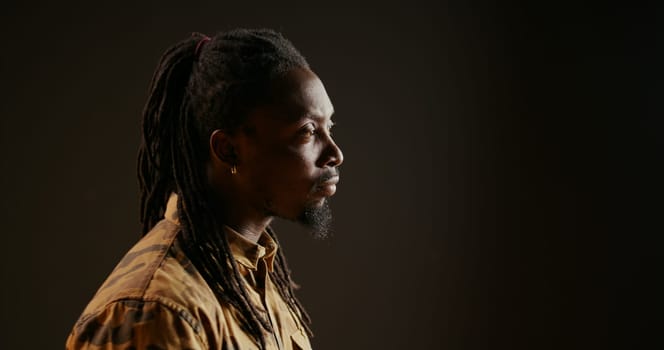 African american person being surprised seeing something in studio, being amazed and admiring view over black background. Male model looking around and feeling shocked, saying wow.