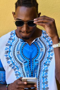 African American teenager adorned in traditional Sudanese clothing, seamlessly navigating the digital world with a smartphone in hand.