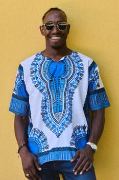 A vibrant portrait of an African American teenager proudly wearing traditional Sudanese clothing against a striking yellow background.