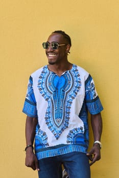 A vibrant portrait of an African American teenager proudly wearing traditional Sudanese clothing against a striking yellow background.