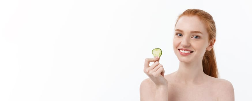 Close up beauty portrait of a smiling beautiful half naked woman holding cucumber slices at her face isolated over white background.