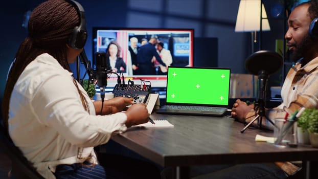 Isolated screen laptop on desk next to presenter on podcast chatting with guest during marathon stream for humanitarian cause. Chroma key notebook used by host to check gathered donations from fans