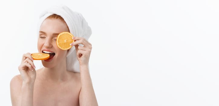 Great food for a healthy lifestyle. Beautiful young shirtless woman holding piece of orange standing against white background