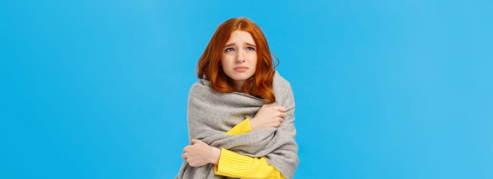 Girl sitting dormitory with broken heater, wrapping herself with warm scarf, looking upset and unwell upper left corner, grimacing suffer discomfort low temprature, catching cold, blue background.