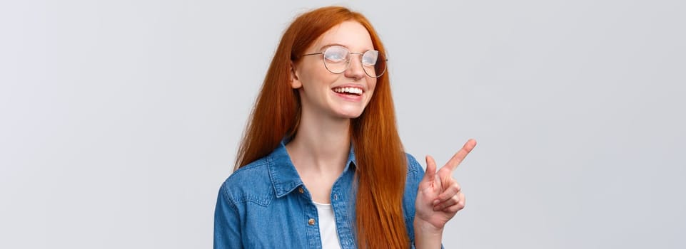 Close-up dreamy and cheerful, excited redhead female in glasses, dreaming about future opportunities, aspire enter famout university, pointing and looking upper left corner happy.