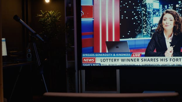 TV left open at night on streaming service channel with news reporter covering different subjects. Close up shot of smart TV in empty dimly lit apartment showing journalist talk about reportages