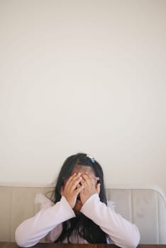 a upset child girl cover her face with hand .