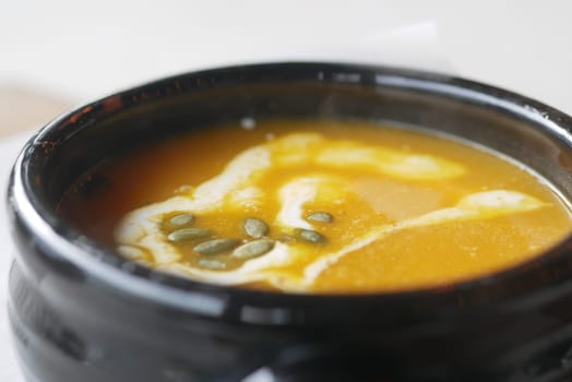 Delicious pumpkin soup in bowl on wooden table