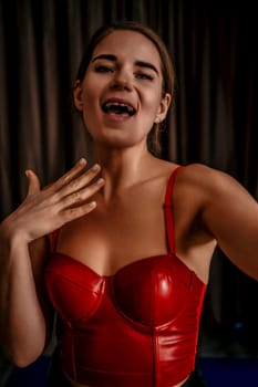 Young woman in red corset and black leather pants. Sexy brunette in red and black costume. Role play. Entertainment