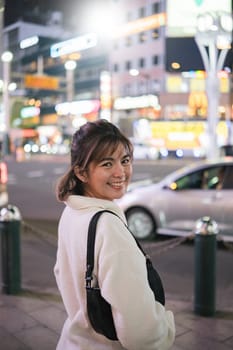 Asian woman smiling in city street at night, Concept of urban nightlife.