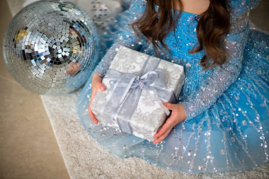 Female hands hold a gift box. Christmas, new year, birthday concept. The girl is dressed in a blue dress and holds out a gift