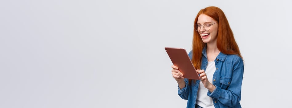 Waist-up porrtrait happy cheerful redhead girlfriend talking to partner using internet video-call service, laughing happily, having fun, smiling at gadget camera, standing white background.