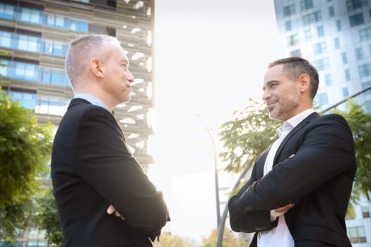 Two colleagues face each other, look seriously work as a team, ready to start a new project, pose outdoors