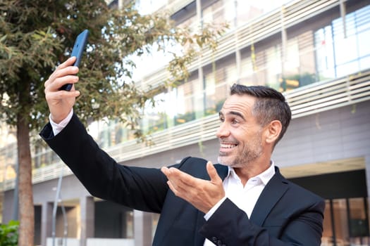 Middle aged man sitting happily taking a selfie with cell phone.