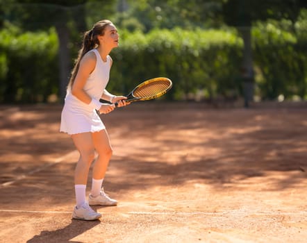 A woman is playing tennis on a clay court. She is wearing a white shirt and a white skirt