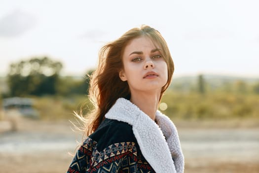 Serene woman with flowing hair standing in a sunlit field at dusk