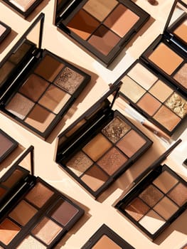 Multiple eyeshadow palettes arranged on a light background, featuring warm brown and gold tones.