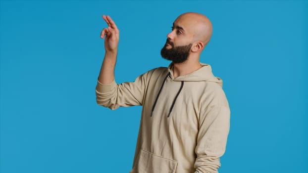 Arab man exploring artificial intelligence with holograms, examining holographic projection of a slideshow in studio. Middle eastern person looks at graphic image on holograph. Camera 1.