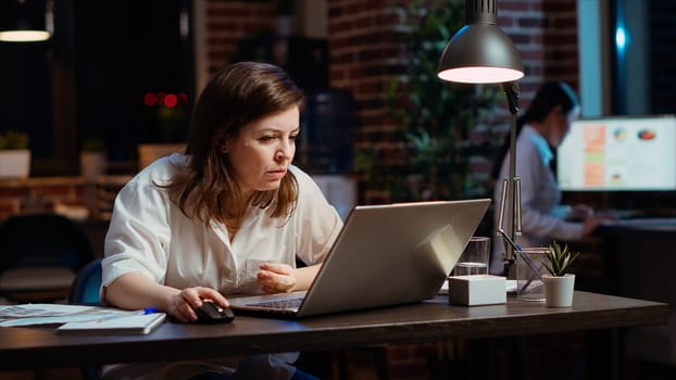 Employee calling manager to her computer desk to ask for feedback on project progress. Worker in office late at night requesting assistance from team leader on tasks done on laptop