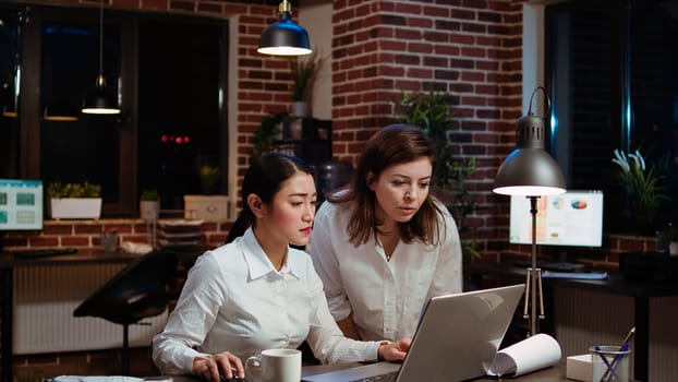 Asian employee brainstorming with coworker to compose email at computer desk, finalizing deal with business partners. Businesswoman and colleague closing agreement with associates, camera A