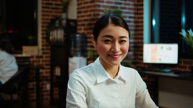 Zoom in on joyful asian employee writing important emails at computer desk, finalizing deal with business partners. Portrait close up shot of happy employee typing on laptop, camera A