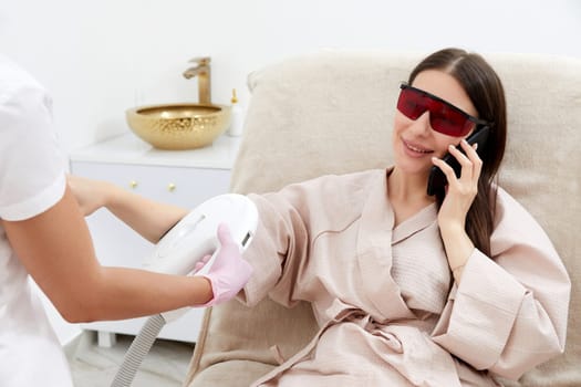 Woman in a beauty salon setting gets her hands treated with laser technology for hair removal