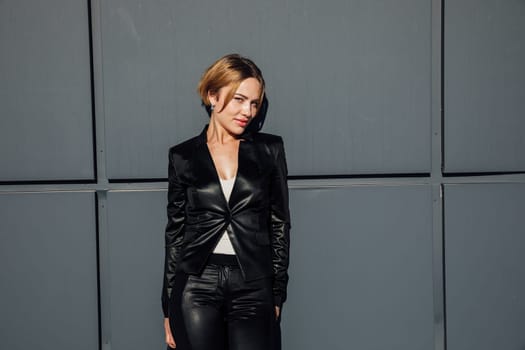 a woman in black leather clothing fashion style against the background of a dark wall