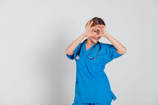 female doctor in blue suit with stethoscope in hospital office shows heart