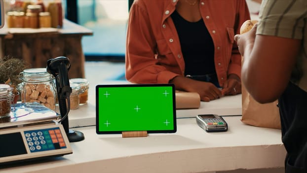 Tablet running display with blank greenscreen at checkout, showing isolated chromakey layout in local grocery store. Merchant having device with copyspace mockup layout, nonpolluting small business.