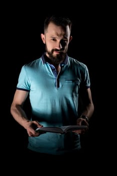 Studio photo of bearded young man with book in his hands