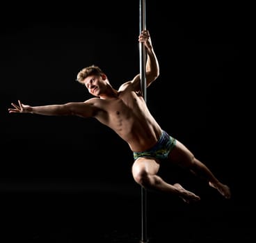 Smiling dancer posing while performing trick on pylon