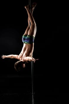 Male pole dance. Image of guy posing upside down on pylon