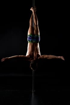 Pole dance. Image of strong man hanging upside down