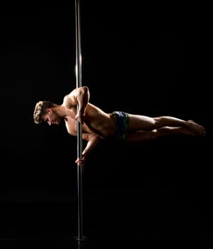 Studio photo of handsome young man dancing on pylon