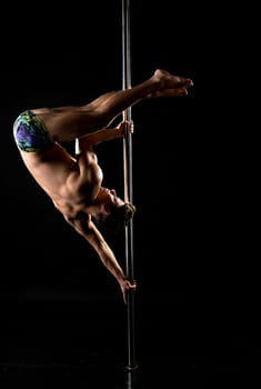 Image of strong guy performs acrobatic trick on pole