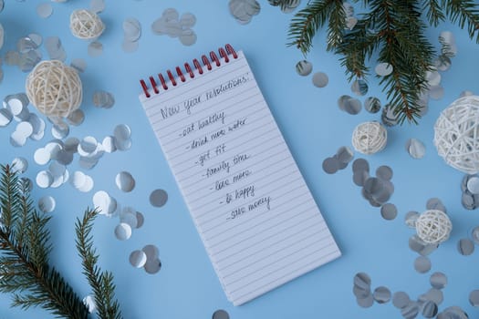 New year's resolutions on paper note with Christmas decor. Making promises for new year, setting goals. Creating dream vision board motivation