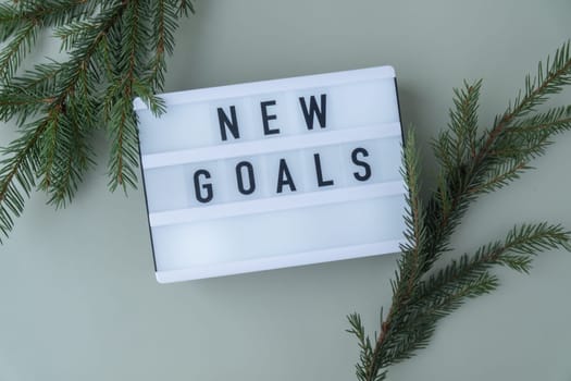 NEW GOALS text on Lightbox on green background with Christmas decor. New year aims resolutions. Planning and setting goals concept