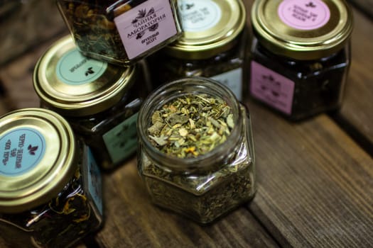 Small jars with various types of green fruit tea standing on a wooden table. High quality photo