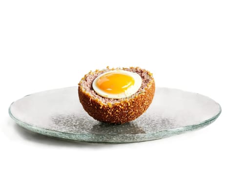 Scotch egg with runny yolk and sausage coating served on a transparent glass plate British. Food isolated on transparent background.