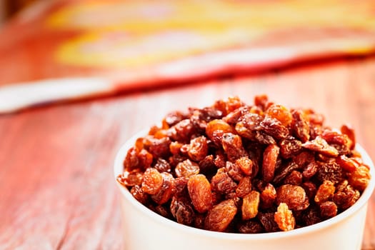  Bunch of raisins in  bowl on wooden table , dried grape fruit eating raw or used in cooking