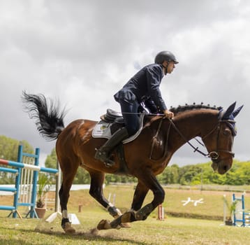 19 may 2024, Mafra, Portugal - competition in military academy - man is riding a horse in a field. The horse is running and the man is wearing a blue jacket