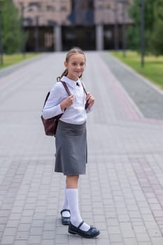 Portrait of caucasian schoolgirl in uniform and with backpack outdoors